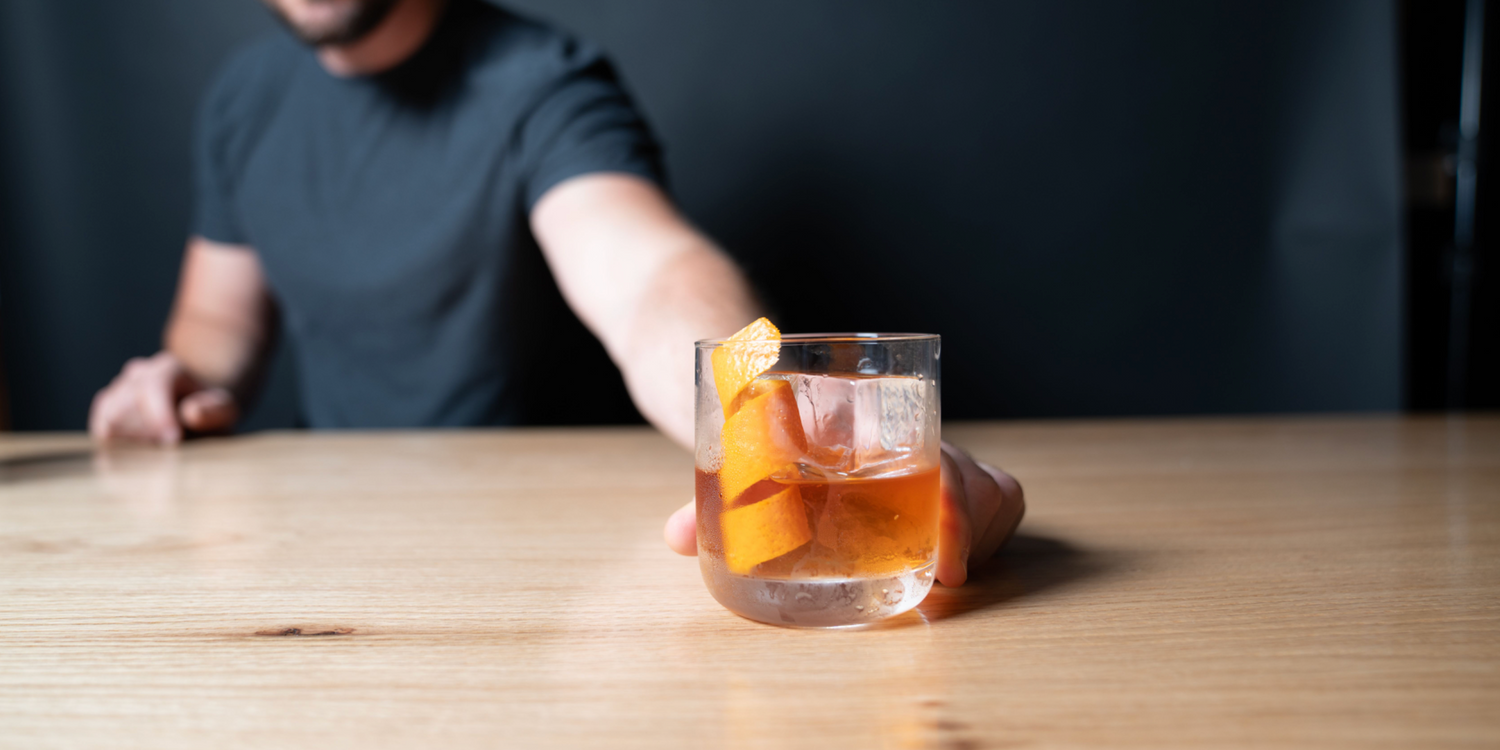 a glass of sons & dotters Old Fashioned being slid across the bar by an arm